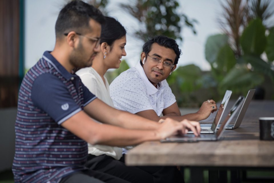 Three people working side by side on laptops