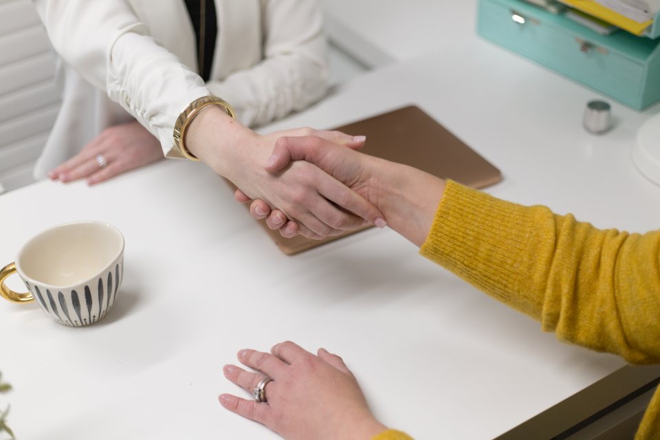 Two people shaking hands across an office desk