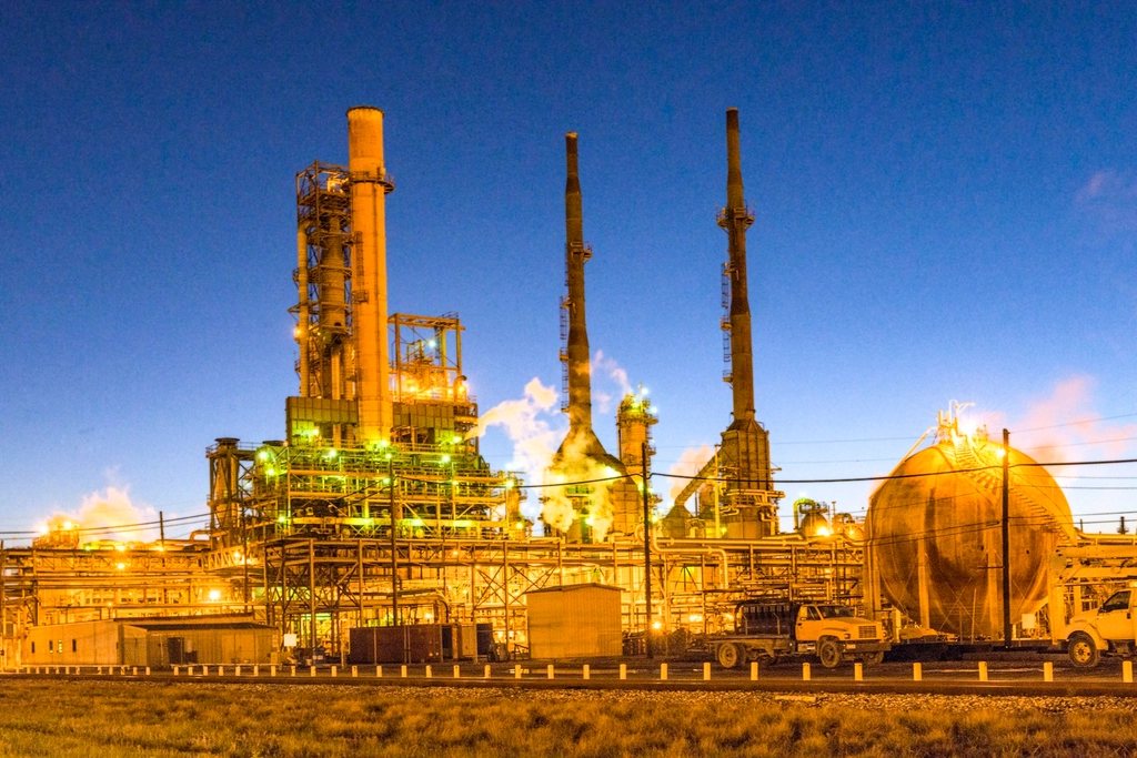An oil refinery's towers and tanks lit up at dusk